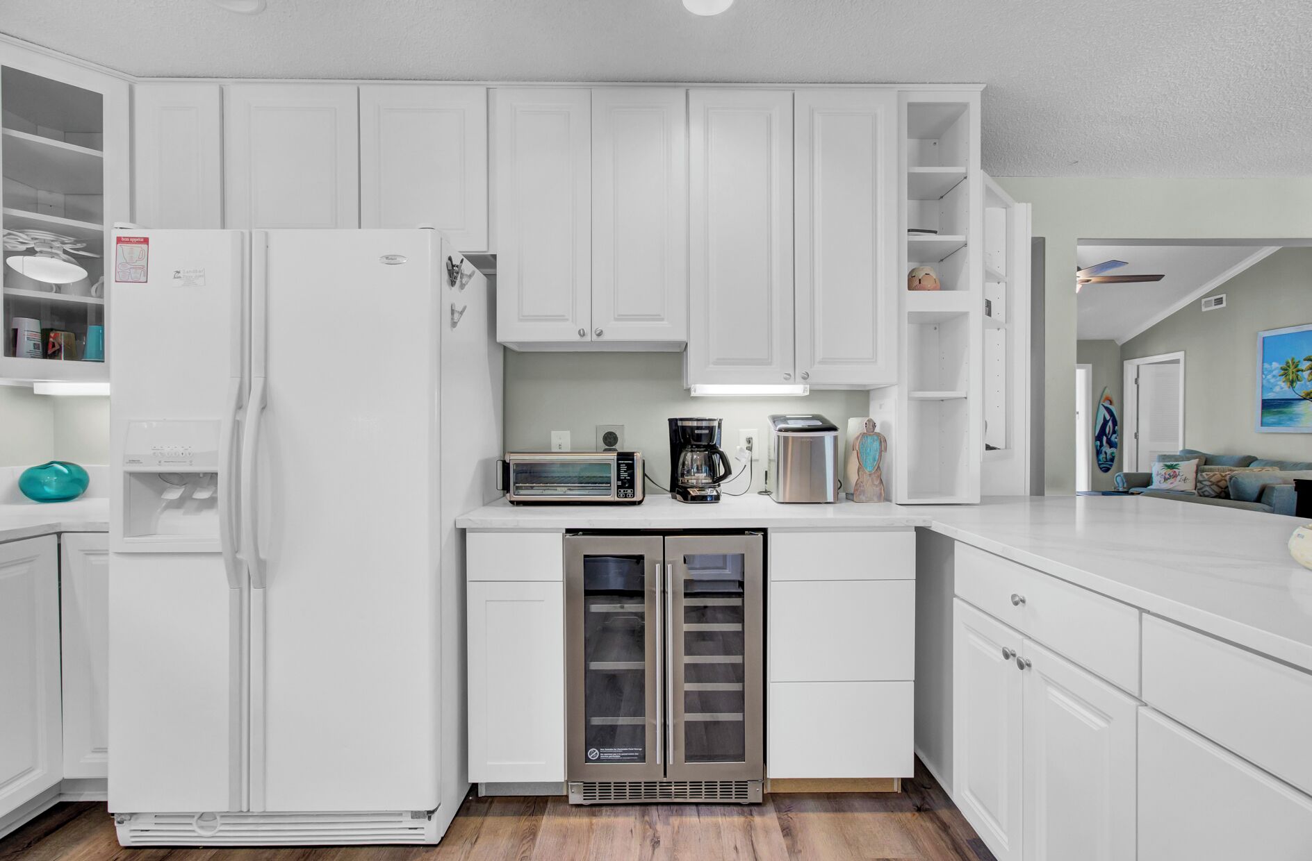 A modern kitchen with white cabinetry, a refrigerator, a microwave, a coffee maker, and a toaster.
