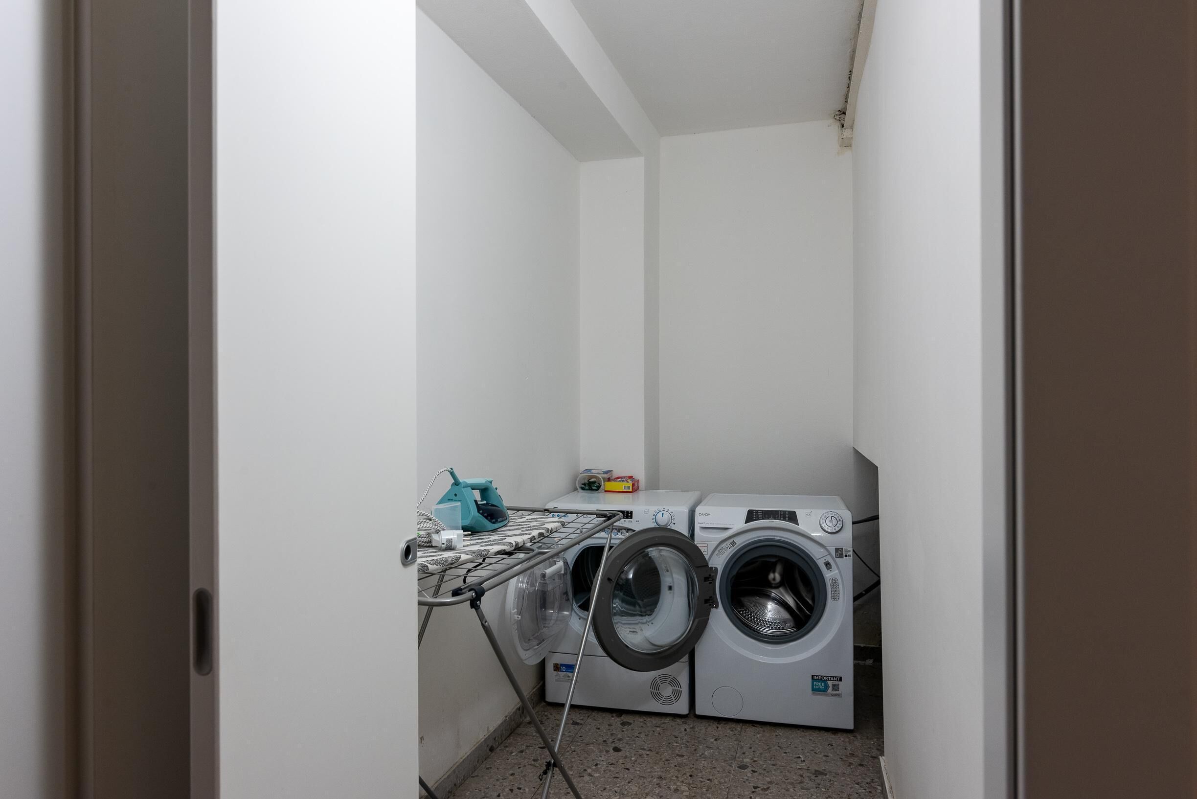 Un cuarto de lavandería con dos lavadoras de carga frontal y un tendedero.