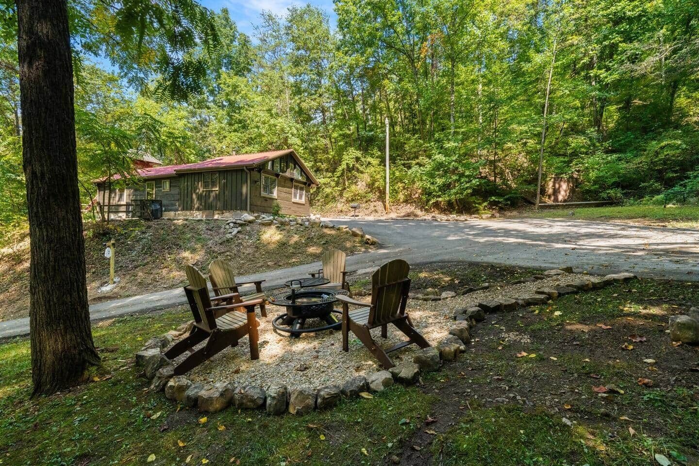 Une cabane avec un foyer et des fauteuils Adirondack, située dans un cadre forestier.