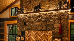 Un intérieur rustique avec une cheminée en pierre, des poutres en bois et une porte ornée d’un motif en chevrons.