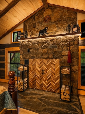 Un interior rústico con chimenea de piedra, vigas de madera y una puerta con patrón de espiga.