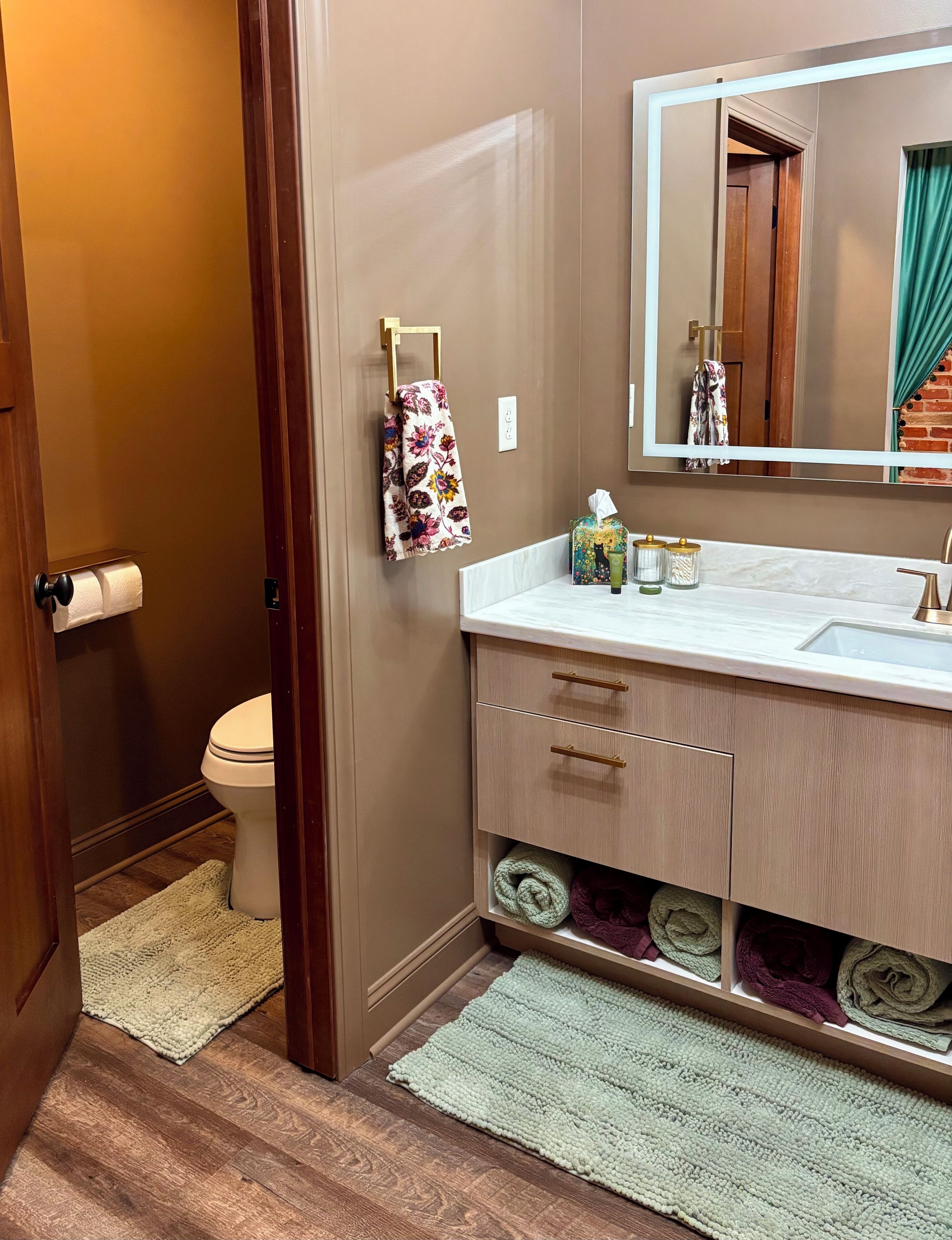 A bathroom with a toilet, a sink with a mirror, and a towel rack.