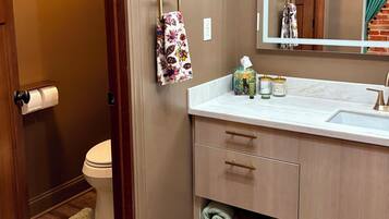 A bathroom with a toilet, a sink with a mirror, and a towel rack.