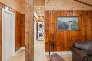 Un interno in legno con un divano, un quadro incorniciato e una zona lavanderia con lavatrici.