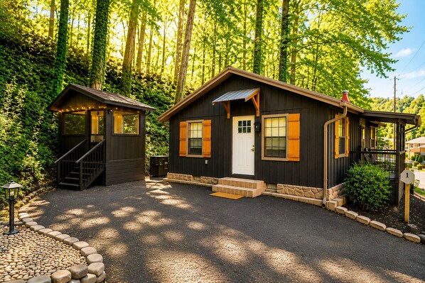 A cabin with a front porch, a staircase, and a small outdoor seating area.