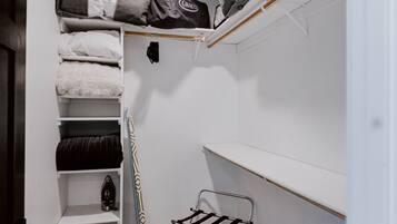 A compact storage room with shelves, a drying rack, and a small ironing board.