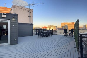 A rooftop terrace with a table and chairs, an exit sign, and a view of the city skyline.
