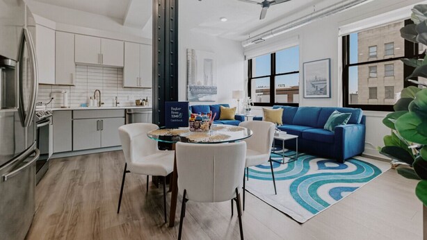 Una sala de estar moderna con un sofá azul, una mesa de centro de vidrio y un tapete azul estampado.