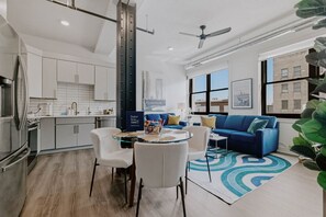 A modern living room with a blue sofa, a glass coffee table, and a blue patterned rug. - Downtown Lincoln Condo, Walk to Haymarket & UNL. (Lincoln)