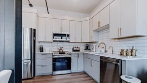 Una cocina moderna con armarios blancos, electrodomésticos de acero inoxidable y piso de madera.
