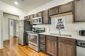 Una cocina moderna con electrodomésticos de acero inoxidable, armarios de madera y encimera blanca.