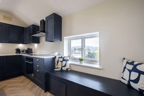 A modern kitchen with dark cabinets, a built-in stove, and a window with a view.