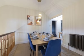 A dining area with a wooden table set for four, blue chairs, and a ceiling with a unique design.