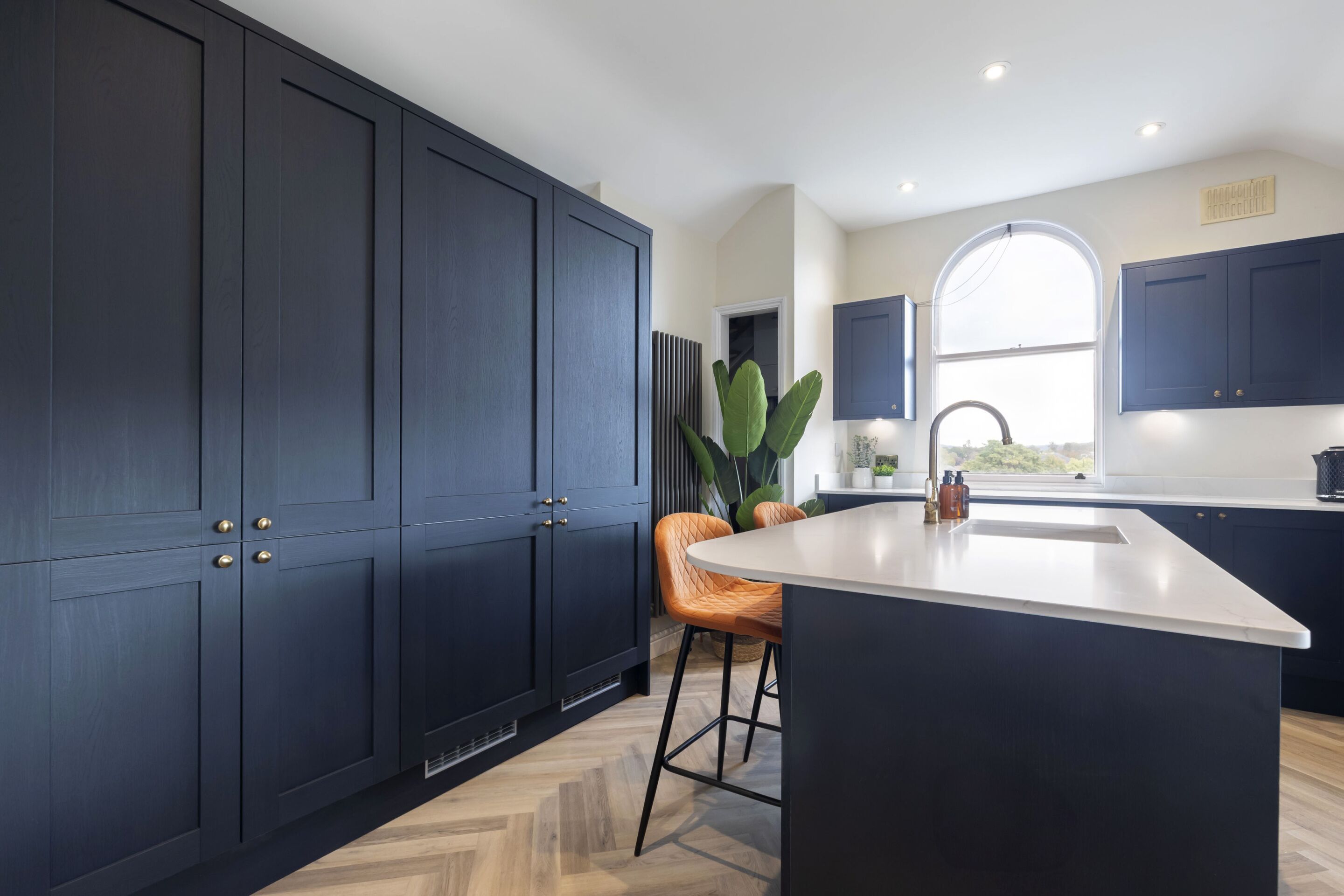 A modern kitchen with dark cabinetry, a large island, and a window providing natural light.