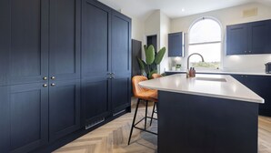 A modern kitchen with dark cabinetry, a large island, and a window providing natural light.