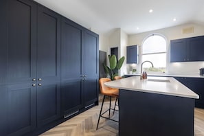A modern kitchen with dark cabinetry, a large island, and a window providing natural light.