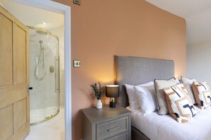Ein Schlafzimmer mit Bett, Nachttisch, Lampe und einer Duschkabine aus Glas.
