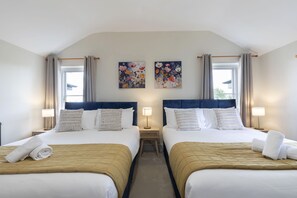 Ein Hotelzimmer mit zwei Betten, jeweils mit Kopfteil, Nachttischen, Lampen und Bildern an der Wand.