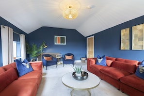A modern living room with two red sofas, a white coffee table, and a blue accent wall.