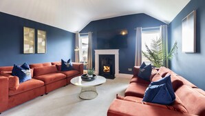 A living room with a fireplace, two sofas, a coffee table, and a large window.
