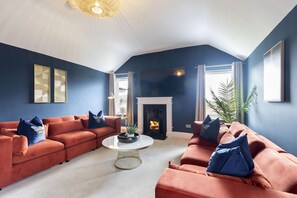 A living room with a fireplace, two sofas, a coffee table, and a large window.
