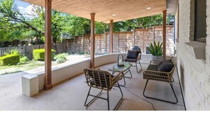 Une terrasse extérieure avec deux fauteuils en osier et une petite table, le tout entouré d’une pergola en bois.