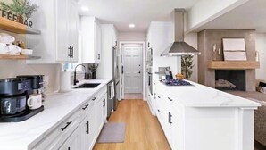 Une cuisine moderne avec des meubles blancs, un îlot central et une cuisinière intégrée.