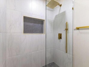 A modern shower with a glass door, a gold showerhead, and a ventilation panel. - Little Gem of White Rock Hills (Dallas)