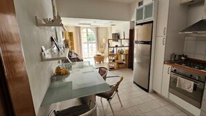 Una cocina con una mesa de comedor, sillas, un refrigerador, un horno y una ventana.