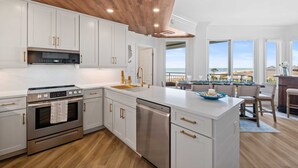 A modern kitchen with white cabinetry, stainless steel appliances, and a wooden ceiling. - SeaCrest 2512 Stunning View, Walk to Coligny Shops & Restaurants (Hilton Head Island)