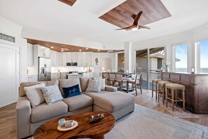 Una cocina moderna con armarios blancos, una isla central y un comedor con una mesa grande y sillas.
