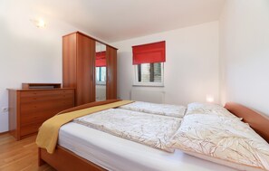 A bedroom with a bed, a wooden dresser, a window with blinds, and a radiator. - Stunning home in Jurdani (Jurdani)