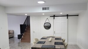 Un comedor con una mesa de madera, sillas y un espejo colgante.