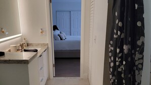 Un pasillo estrecho que conduce a un dormitorio con cama, un baño con bañera y una zona de ducha.