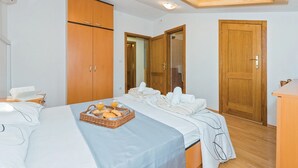 Een hotelkamer met een bed, een houten kledingkast, een badkamers deur en een ontbijtserver op het bed.
