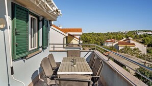 A balcony with a table and chairs, overlooking a residential area with houses and greenery. - 1 bedroom cozy apartment in Sibenik (Sibenik)