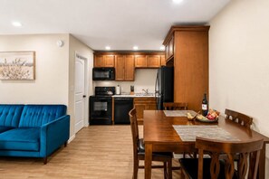 A compact kitchen with a dining area, a blue sofa, and a painting on the wall.