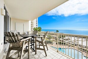 A balcony with a view of the ocean and a pool.