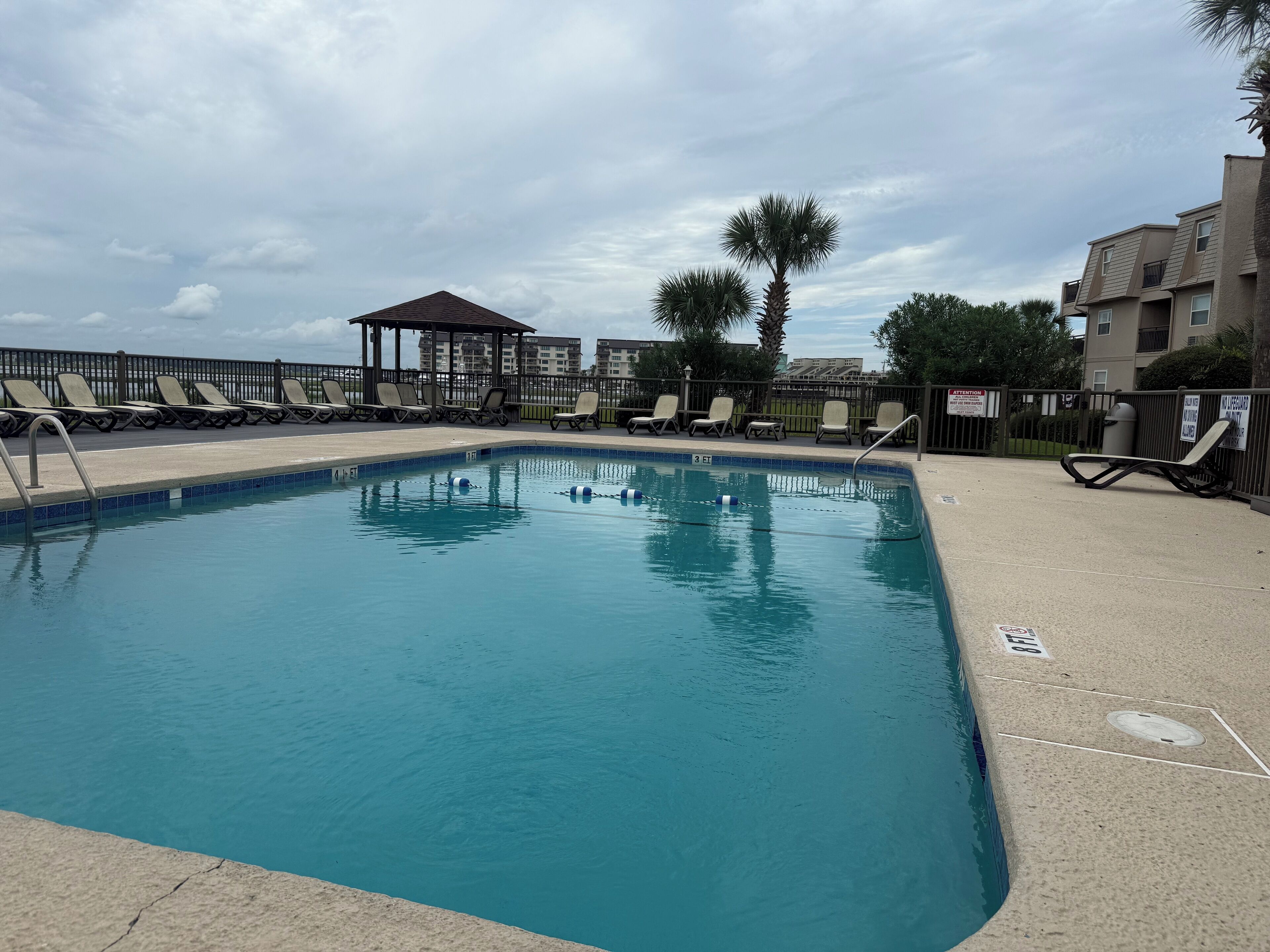 Una piscina con lettini e un gazebo.