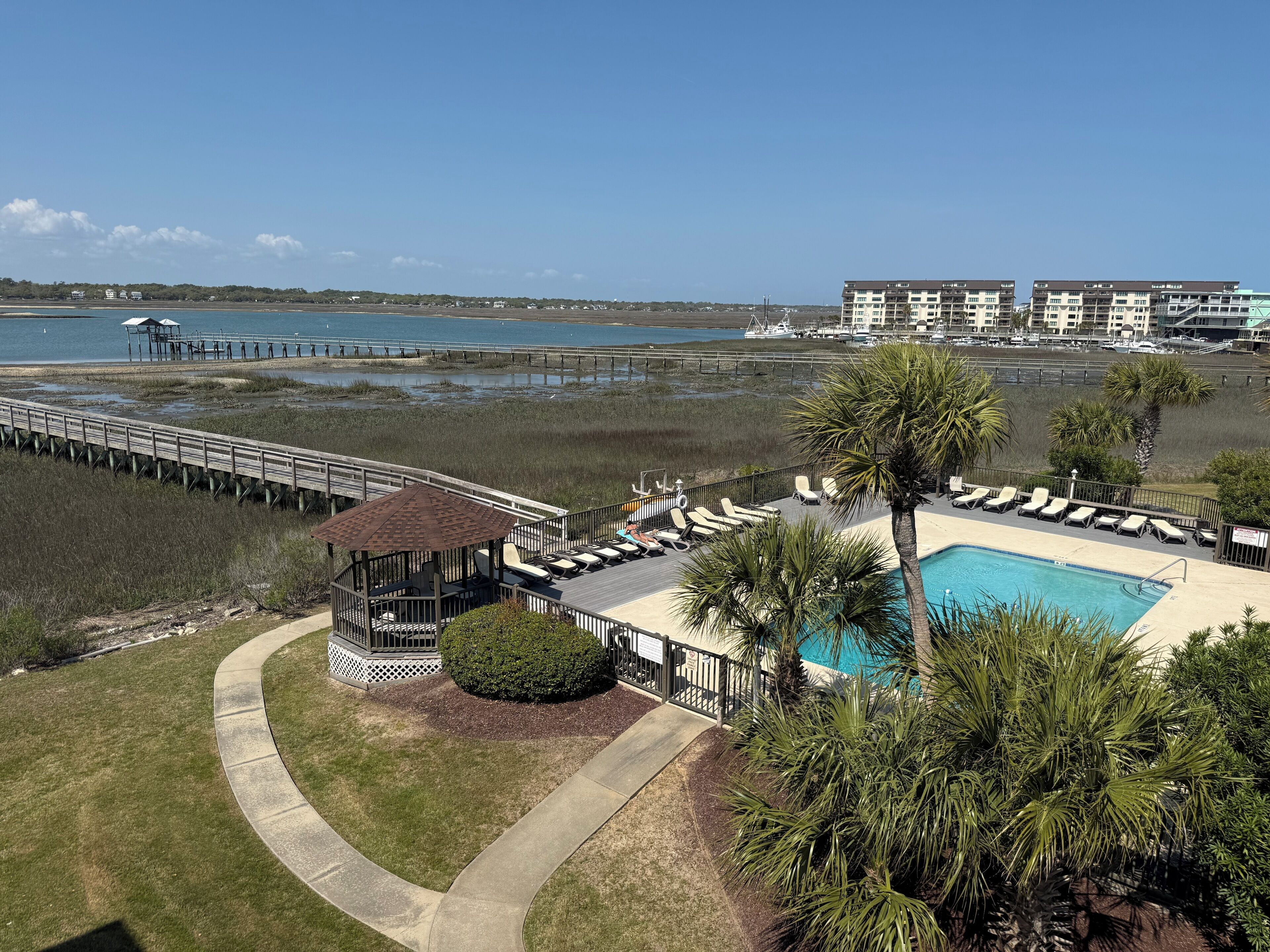 Un complexe hôtelier doté d’une piscine, de chaises longues, d’une terrasse et offrant une vue sur la plage et l’océan.
