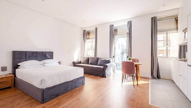 A modern hotel room with a large bed, a sofa, a dining area, and a kitchen. - House Steps from Porto’s Best Attractions (Vila Nova de Gaia)