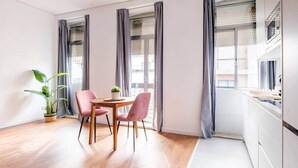 A modern kitchen with white cabinets, a wooden countertop, and a window with grey curtains. - House Steps from Porto’s Best Attractions (Vila Nova de Gaia)