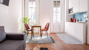 A compact living space with a dining area, a kitchen with a microwave, and a grey sofa. - House Steps from Porto’s Best Attractions (Vila Nova de Gaia)