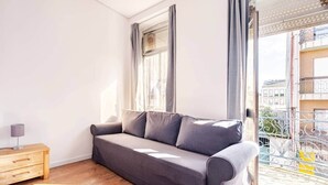 A modern living room with a grey sofa, wooden side table, and a view of a balcony with metal railings. - House Steps from Porto’s Best Attractions (Vila Nova de Gaia)
