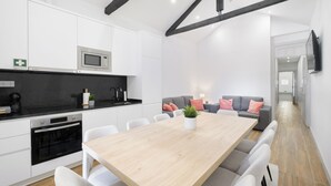 Une cuisine moderne avec des meubles blancs, un four à micro-ondes encastré et une table à manger en bois avec des chaises.