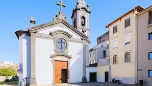 A church with a bell tower, a wooden door, and a cross on top. - Riverside Studio By Luís Bridge, WOW & Half Rabbit (Vila Nova de Gaia)