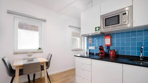 A compact kitchen with a microwave, kettle, and a small dining area with a table and chairs. - Riverside Studio By Luís Bridge, WOW & Half Rabbit (Vila Nova de Gaia)