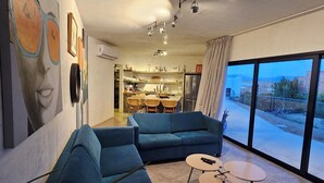 A modern living room with a blue sofa, two round tables, and a large window with a view. - CASA ZORRO Close to the hot springs, bike trails and beautiful beach. (El Sargento)