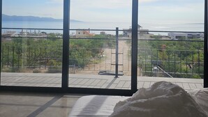 A bedroom with a large window overlooking a landscaped area with a view of distant buildings and mountains. - CASA ZORRO Close to the hot springs, bike trails and beautiful beach. (El Sargento)