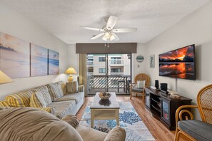 A living room with a sofa, coffee table, TV, and artwork on the walls. - Cozy 2BR Condo at Shipwatch Pointe Condos! (Myrtle Beach)